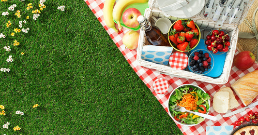 picnic food on a red white grid cloth on green grass