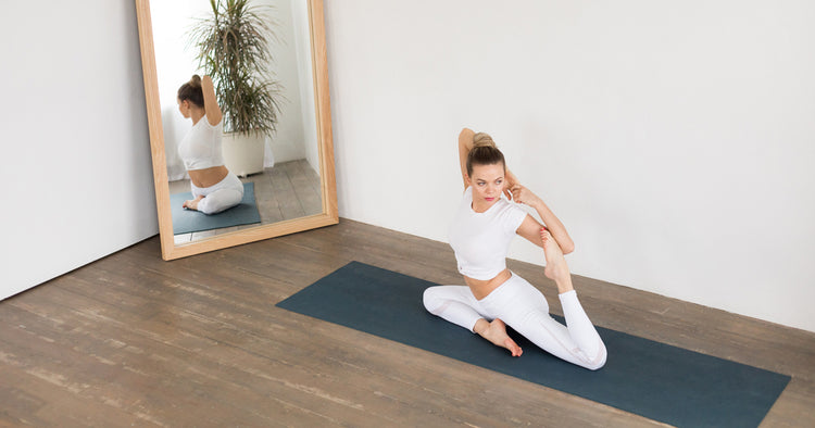 a woman is stretching on yoga mat in front of mirror