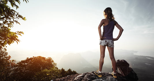 a woman stands on the top of mountain