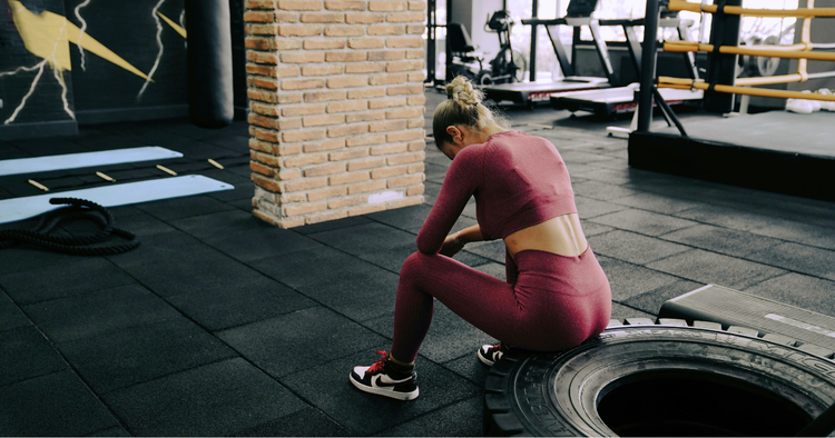 woman sits on exercise tire discouraged unmotivated to workout