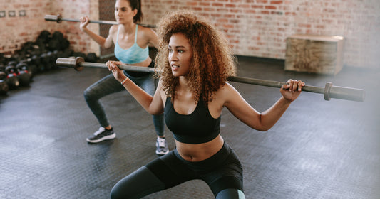 woman exercising with barbell in fitness class