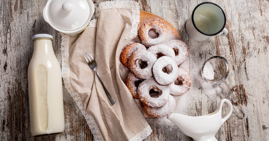 homemade baked doughnuts with glazing and powdered sugar covered with a white cotton blanket on a vintage background