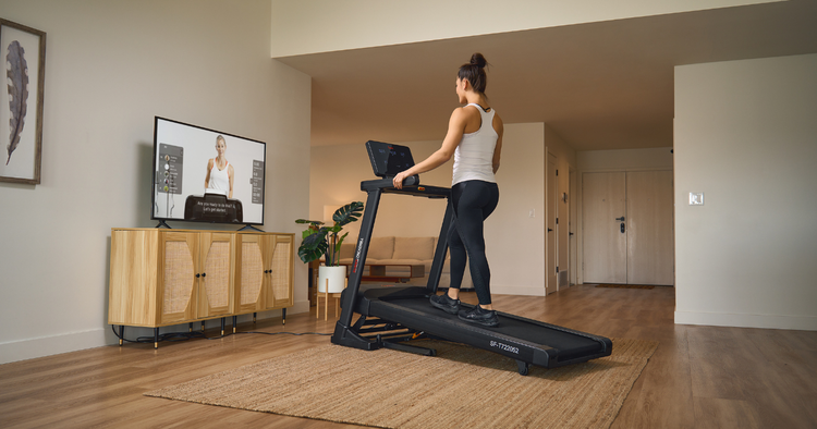 woman incline walks on treadmill in living room and follows workout