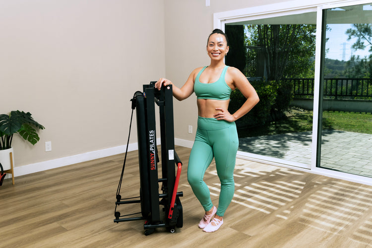 Woman standing with reformer Pilates machine.