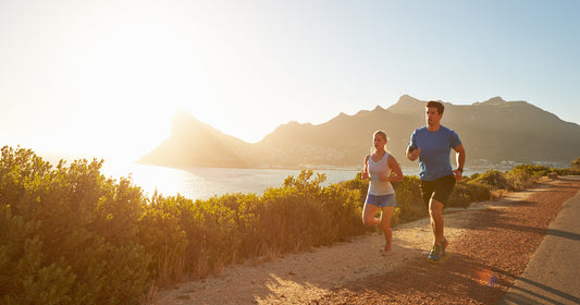 two people are running in a lake park under sunshine