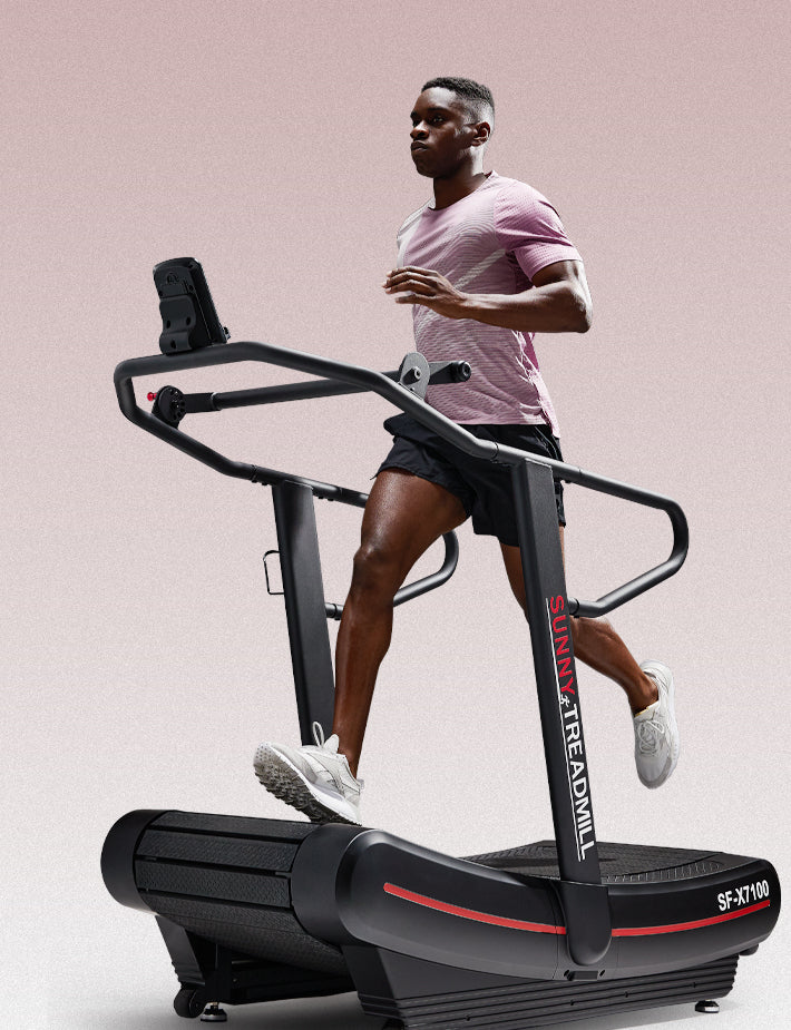 Man running on manual treadmill on a pink gray background